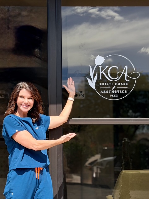 Kristi Chase, RN, holding open the front door at Kristi Chase Aesthetics, Tucson